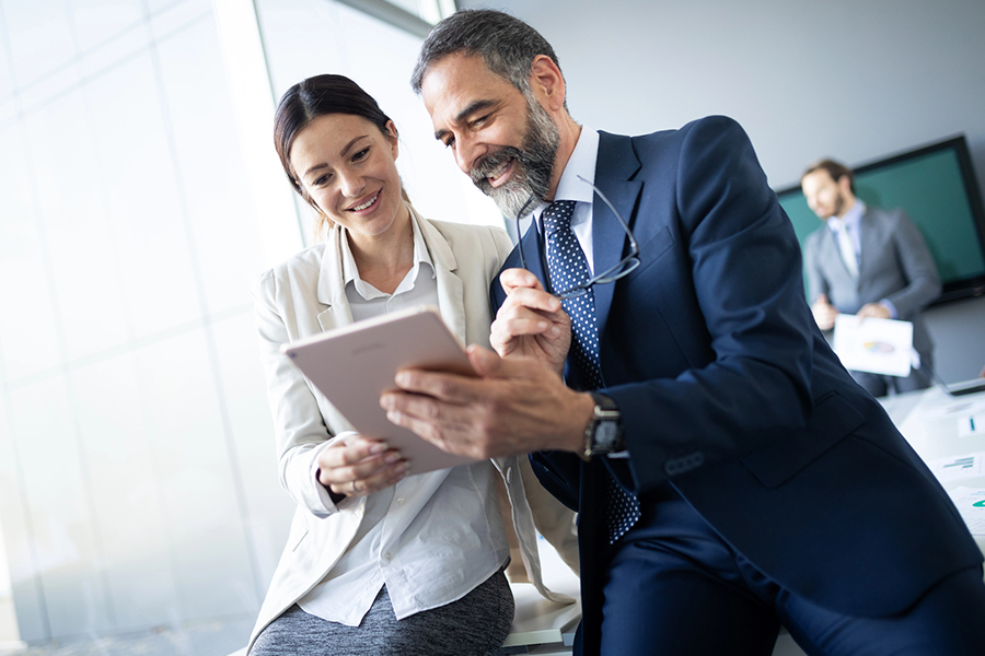 Business professionals collaborating on ROI-focused IT strategies using a tablet in a modern office setting