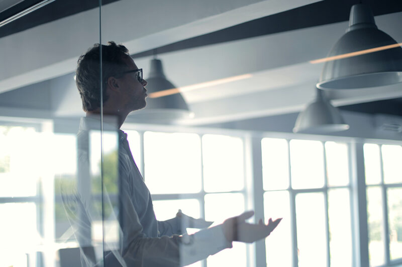 Close-up of IT project manager speaking during a meeting, observed through glass