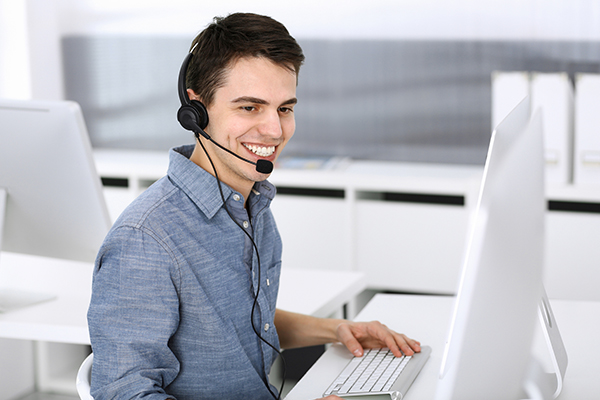 IT support professional in Tokyo assisting a client remotely with a headset and computer.