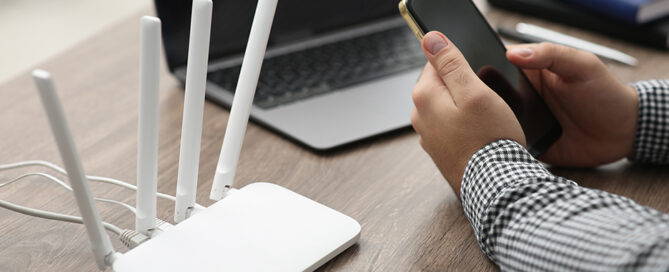 Man using smartphone and laptop to connect to a network, illustrating wifi design best practices