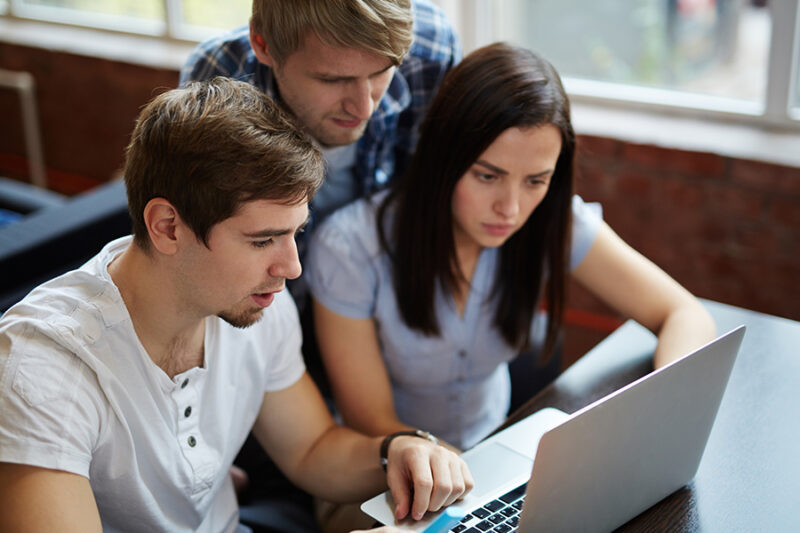 Three local IT experts collaborating on a laptop in an office setting